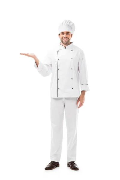 Sonriente joven chef apuntando al espacio en blanco y mirando a la cámara aislada en blanco - foto de stock