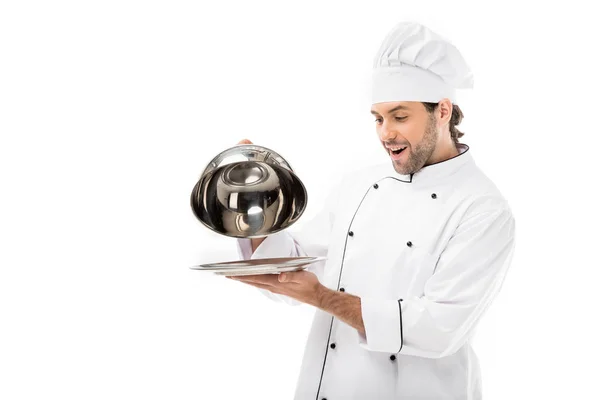 Surpresa jovem chef tendo de servir cúpula de prato isolado em branco — Fotografia de Stock