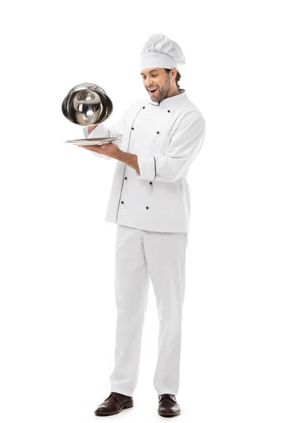 Expressed young chef taking of serving dome from plate isolated on white — Stock Photo