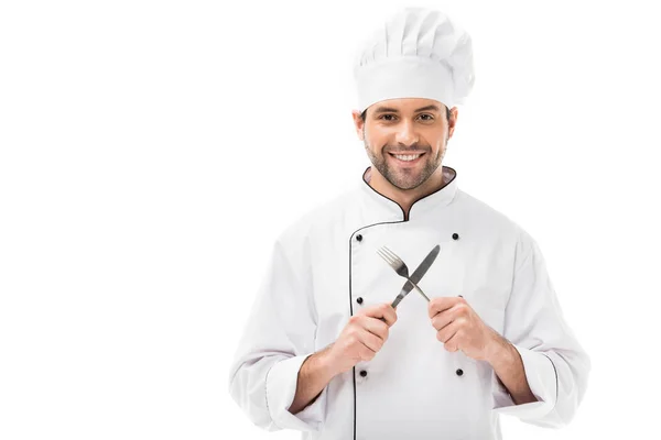 Souriant jeune chef tenant fourchette et couteau et regardant la caméra isolée sur blanc — Photo de stock