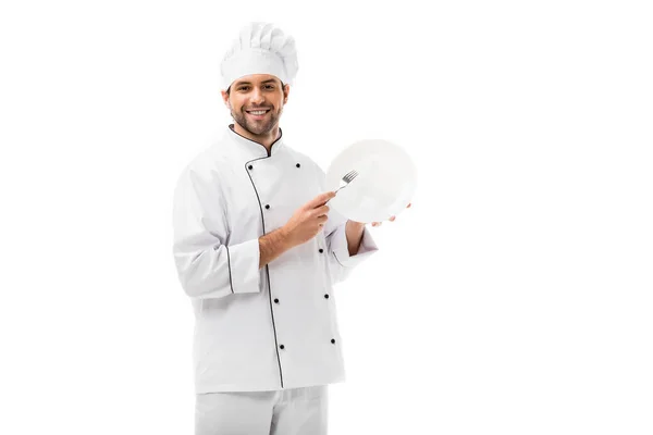 Handsome young chef with plate and fork looking at camera isolated on white — Stock Photo