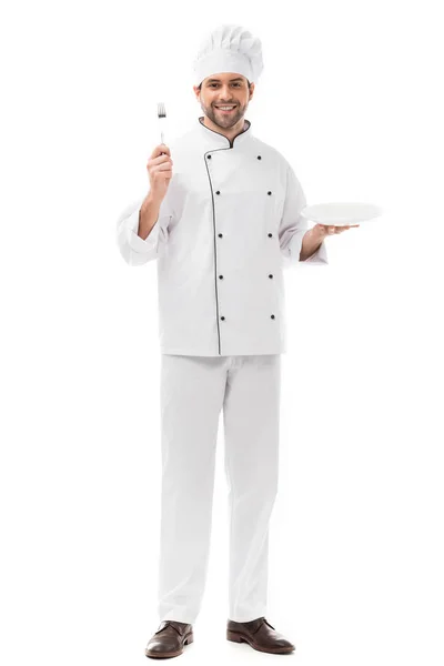 Happy young chef with plate and fork looking at camera isolated on white — Stock Photo