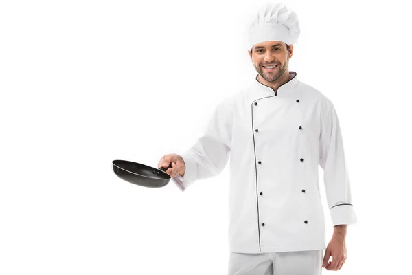 Smiling young chef holding frying pan and looking at camera isolated on white — Stock Photo