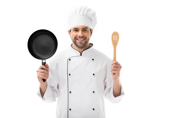 Jovem chef feliz segurando frigideira e espátula de madeira isolada em branco — Fotografia de Stock