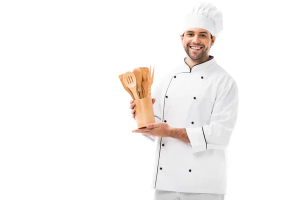 Smiling young chef with bunch of wooden kitchen utensils isolated on white — Stock Photo