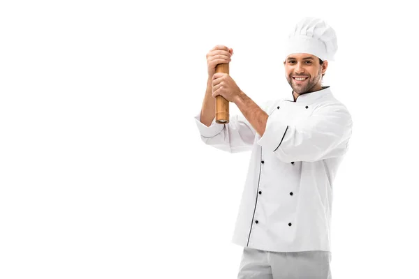 Smiling young chef using bamboo pepper mill isolated on white — Stock Photo
