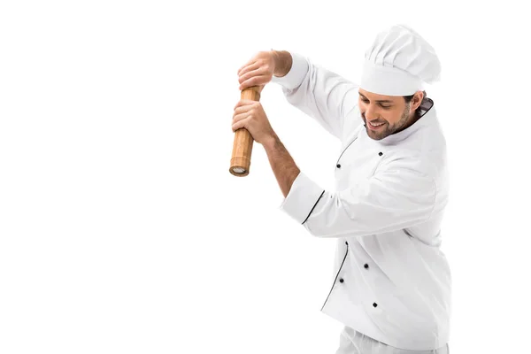 Sonriente joven chef con molino de pimiento de bambú aislado en blanco - foto de stock