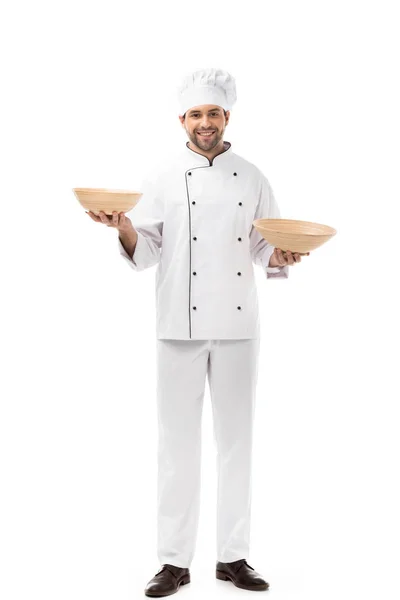 Smiling young chef holding bowls isolated on white — Stock Photo