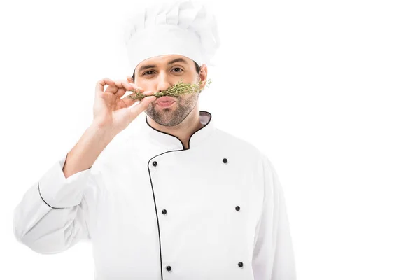 Divertido joven chef haciendo bigote con tomos y mirando a la cámara aislada en blanco - foto de stock