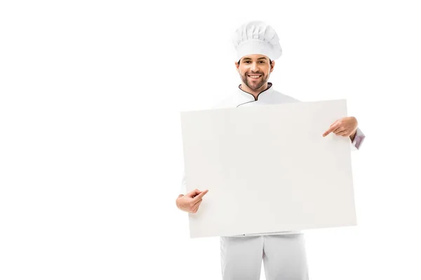 Chef profesional apuntando con el dedo a la pancarta en blanco y sonriendo a la cámara aislada en blanco - foto de stock