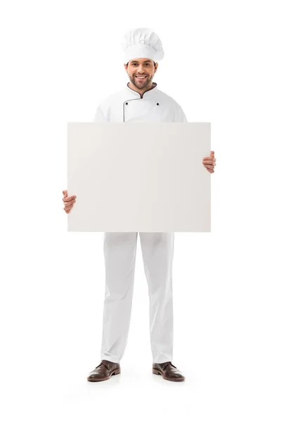 Full length view of handsome male cook holding blank placard and smiling at camera isolated on white — Stock Photo