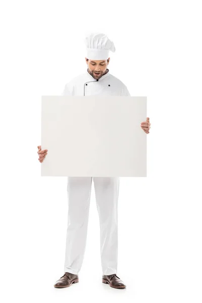 Cocinero masculino profesional sosteniendo pancarta en blanco y mirando hacia abajo aislado en blanco - foto de stock