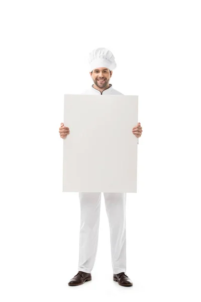 Guapo joven chef sosteniendo pancarta en blanco y sonriendo a la cámara aislada en blanco - foto de stock