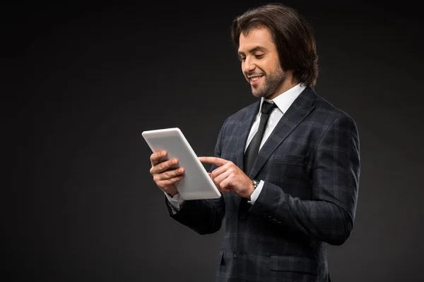 Professionale sorridente giovane uomo d'affari utilizzando tablet digitale isolato su nero — Foto stock