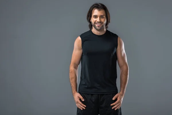 Portrait de beau jeune homme athlétique en tenue de sport souriant à la caméra isolé sur gris — Photo de stock