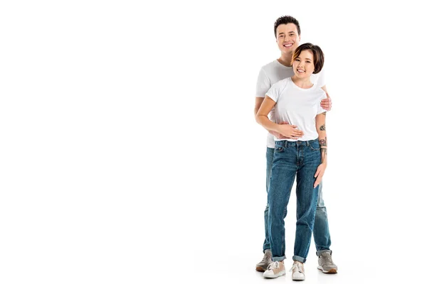 Novio amoroso mirando a la cámara y abrazando novia sonriente aislado en blanco - foto de stock