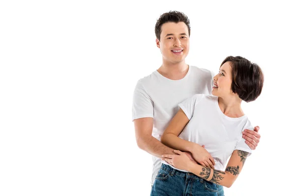 Smiling boyfriend hugging girlfriend and looking at camera isolated on white — Stock Photo