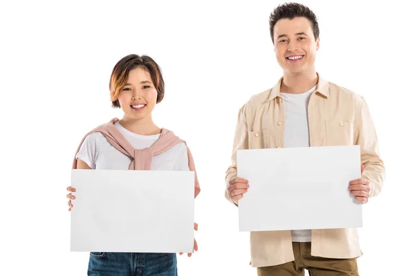 Lächelndes Ehepaar in lässiger Kleidung, das in die Kamera blickt und zwei leere Bretter auf weißem Grund hält — Stockfoto