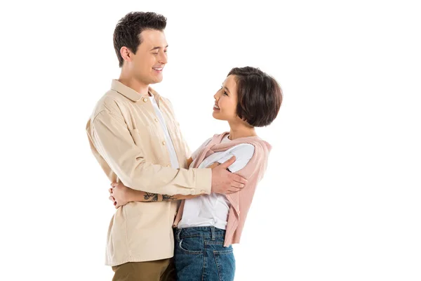 Lächelnder Ehemann und schöne Frau in lässiger Kleidung umarmen sich und schauen einander isoliert auf weißem Grund an — Stockfoto
