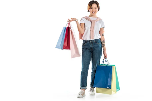 Happy young woman holding shopping bags and looking at camera isolated on white — Stock Photo