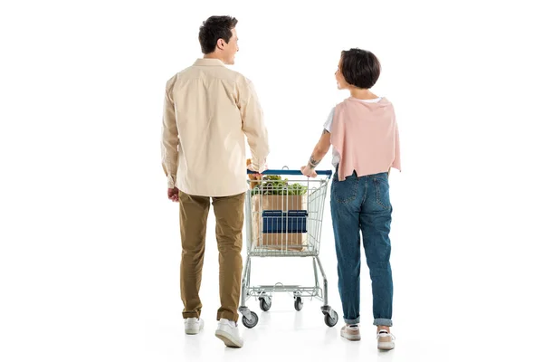 Vista posterior de marido y mujer con carrito de compras aislado en blanco - foto de stock