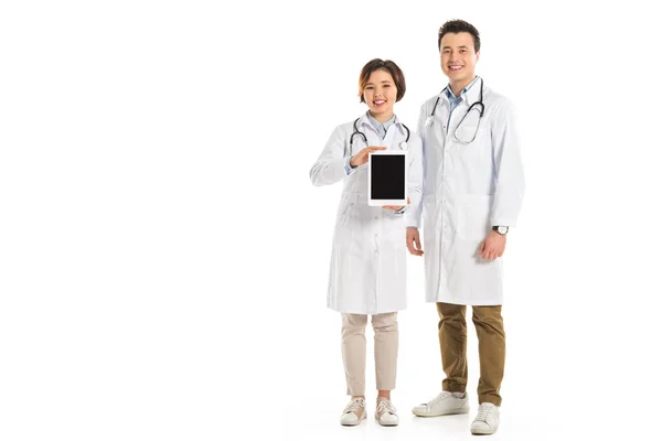 Female and male doctors presenting digital tablet with blank screen isolated on white — Stock Photo