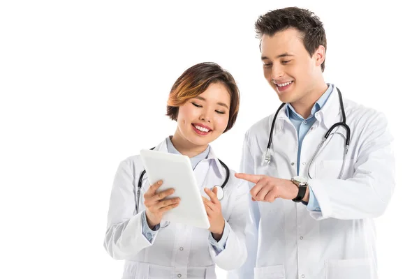Усміхнені жіночі та чоловічі лікарі зі стетоскопами з використанням цифрового планшета ізольовані на білому — стокове фото
