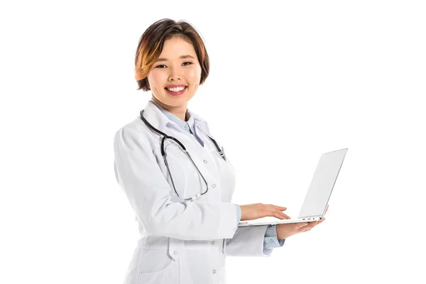 Врач-женщина в стетоскопе смотрит в камеру и держит ноутбук изолированным на белом — стоковое фото
