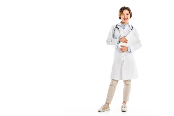 Souriant médecin féminin regardant la caméra, debout et tenant le diagnostic isolé sur blanc — Photo de stock
