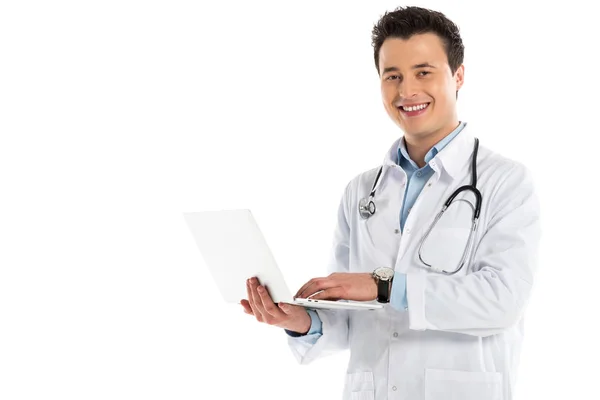 Усміхнений чоловік лікар тримає ноутбук і дивиться на камеру ізольовано на білому — стокове фото
