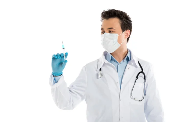 Guapo doctor masculino en guantes de goma y mascarilla que sostiene la jeringa aislada en blanco - foto de stock