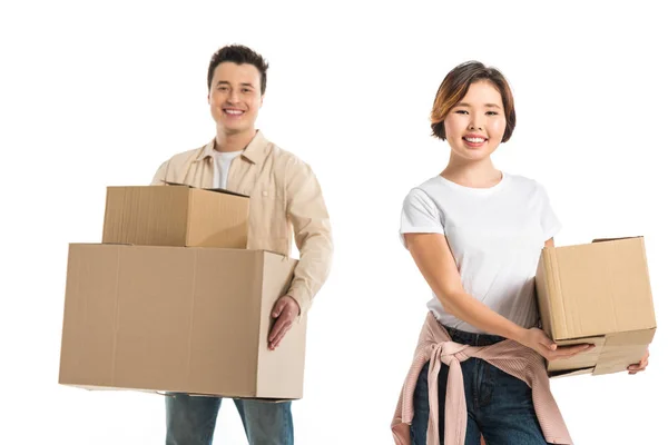 Happy couple looking at camera and holding cardboard boxes isolated on white, moving to new house concept — Stock Photo
