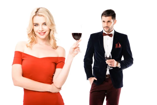 Paar lächelnde blonde Frau und ernster Mann mit Weingläsern auf weißem Grund — Stockfoto