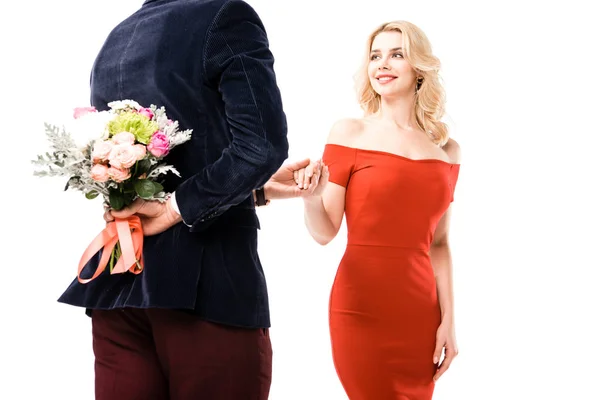 Back view of man with flowers behind back holding hand of girlfriend isolated on white — Stock Photo