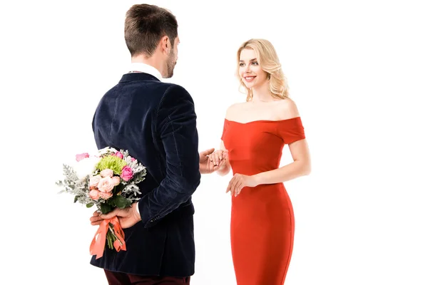 Visão traseira do homem com flores atrás das costas segurando as mãos da namorada no branco — Fotografia de Stock