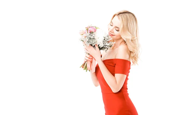 Atractiva mujer en vestido rojo oliendo flores aisladas en blanco - foto de stock