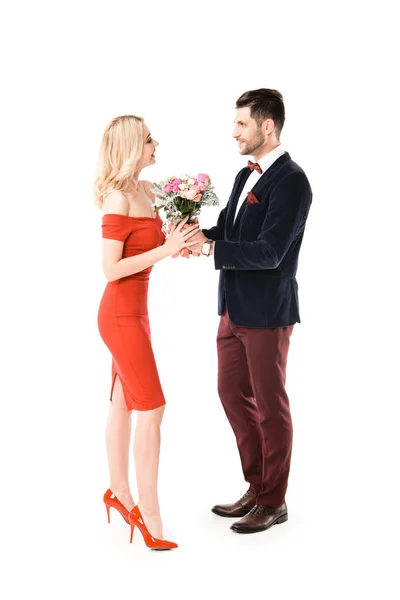 Vista lateral do homem de terno dando flores para a bela namorada isolada no branco — Fotografia de Stock