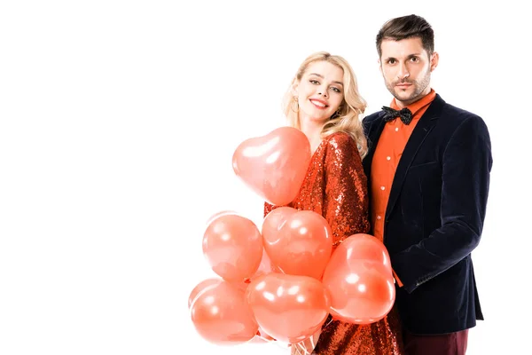 Attraente giovane coppia con palloncini rossi isolati su bianco — Foto stock