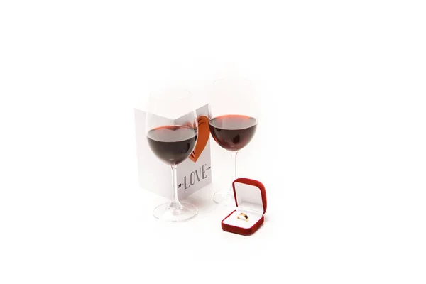Два бокала с красным вином, прекрасная открытка с сердцем и кольцом коробка изолированы на белом — стоковое фото