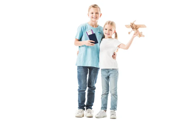 Sister and brother standing with passport and plane model isolated on white — Stock Photo