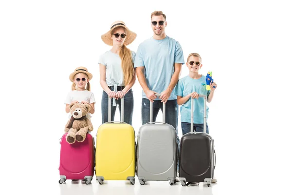 Familia feliz de pie con equipaje colorido y sonriente aislado en blanco - foto de stock
