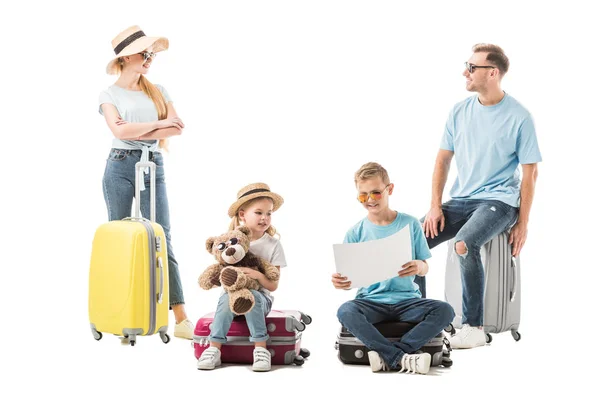 Família sentada na bagagem e olhando para o mapa isolado no branco — Fotografia de Stock
