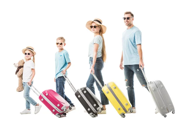 Familia feliz caminando con equipaje colorido y sonriendo aislado en blanco - foto de stock