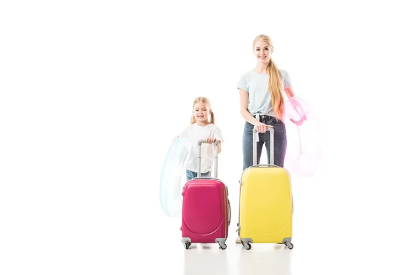 Madre e hija de pie juntas y sosteniendo el equipaje aislado en blanco - foto de stock