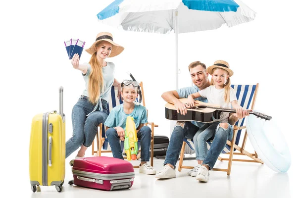 Familia alegre sentada en tumbonas con equipaje en blanco - foto de stock
