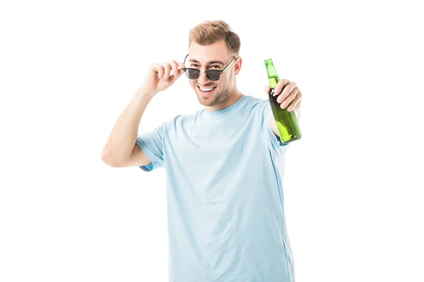 Cheerful man standing and holding bottle with beer isolated on white — Stock Photo