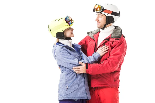 Sorridente coppia in abiti da sci che si abbracciano e si guardano l'un l'altro isolati su bianco — Foto stock