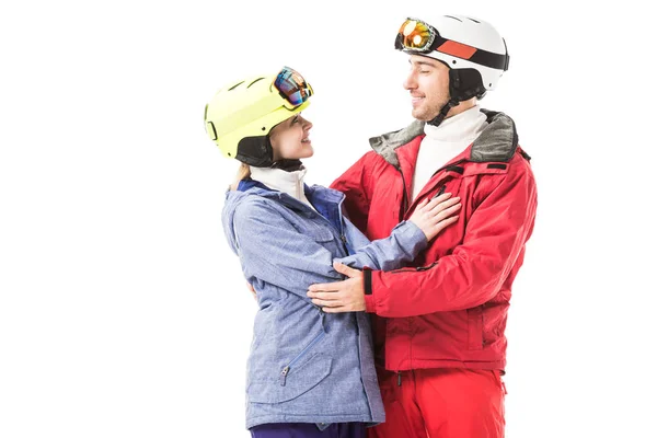 Pareja sonriente en ropa de esquí abrazándose y mirándose aislados en blanco - foto de stock