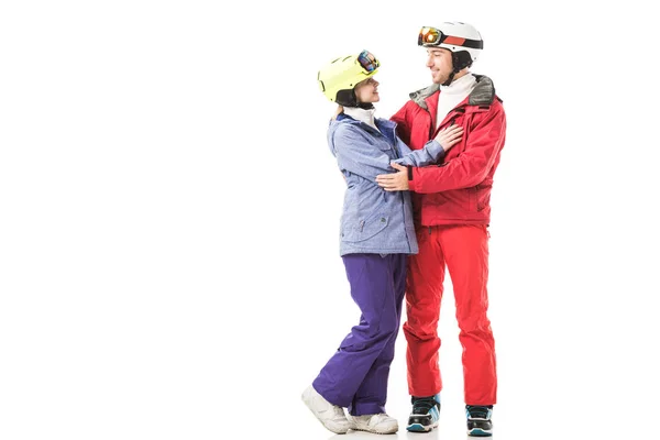 Paar in Skianzügen umarmte sich, lächelte und sah sich vereinzelt auf weißem Grund an — Stockfoto