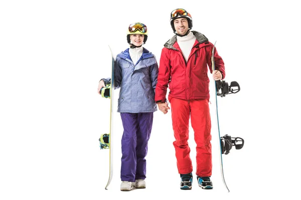 Couple in ski clothes with snowboards holding hands and looking at camera isolated on white — Stock Photo